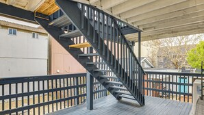 Eine Holzterrasse mit einer Metalltreppe, die zu einer oberen Ebene führt.