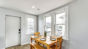 Ein Esszimmer mit einem Holztisch, gedeckt für vier Personen, einer Bank und einem Blumentopf.