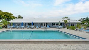 A swimming pool with lounge chairs and umbrellas, a building with a flat roof, and palm trees. - Bonita Beach 7 Mi: 55+ Community w/ Pool Access (Bonita Springs)