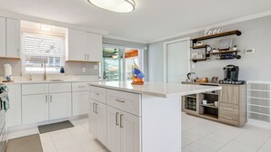 Uma cozinha moderna com armários brancos, uma ilha central e um forno embutido.