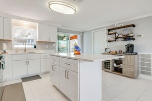 A modern kitchen with white cabinetry, a central island, and a built-in oven. - Canal-Front Oasis in Hudson: Patio + Private Dock! (Hudson)