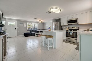 A modern kitchen with white cabinets, stainless steel appliances, and a central island with stools. - Canal-Front Oasis in Hudson: Patio + Private Dock! (Hudson)