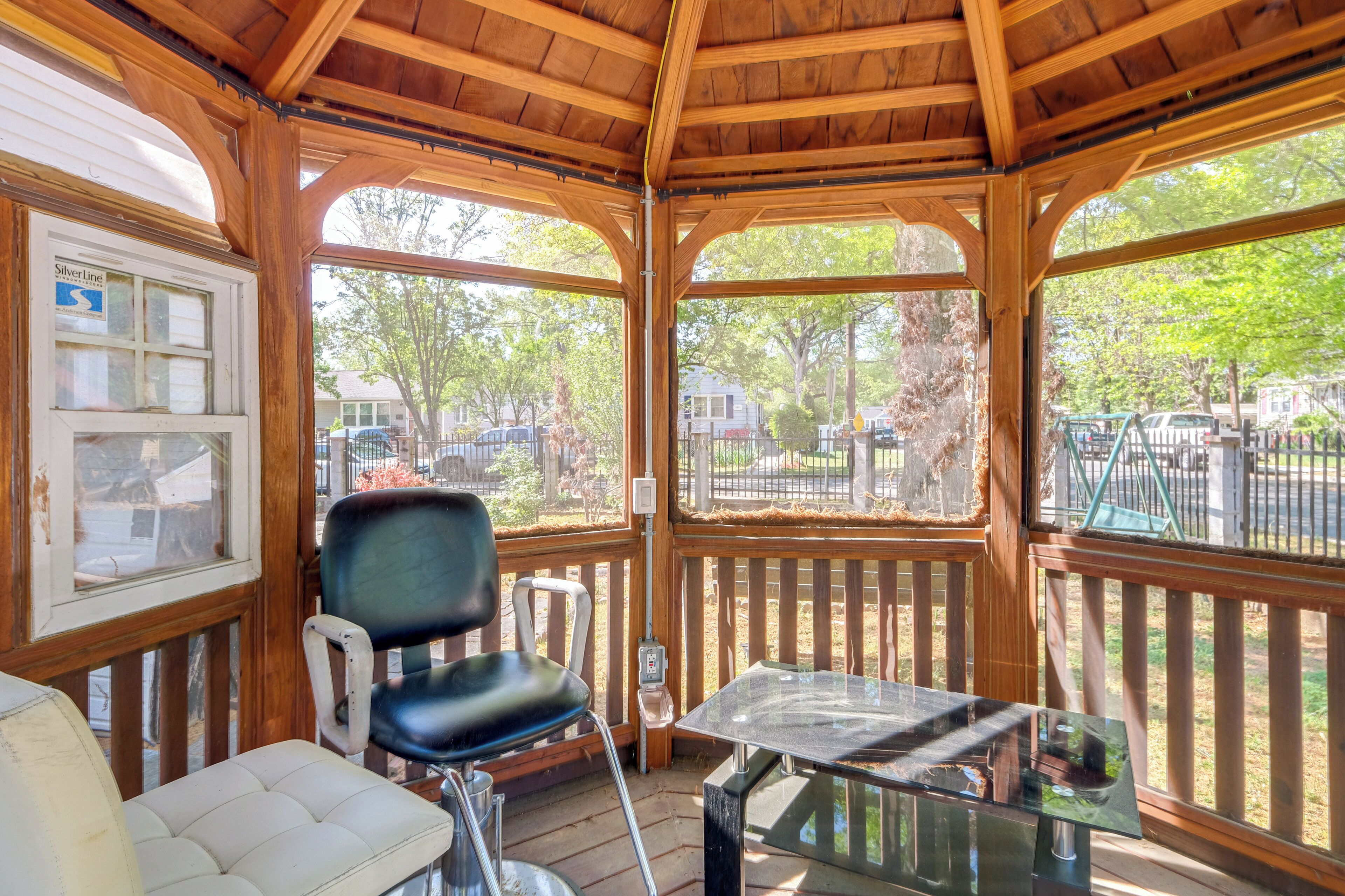 Un espace extérieur abrité, aménagé avec une table et des chaises, des poutres en bois et offrant une vue sur les environs.