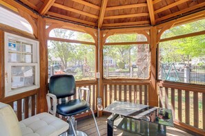 A covered outdoor seating area with a table and chairs, wooden beams, and a view of the surrounding area.