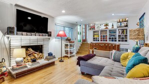 Een woonkamer met een open haard, een televisie, een bank en een boekenkast.