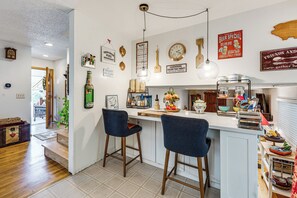 A kitchen with a bar area, wooden stools, a coffee machine, and various kitchen utensils. - Eclectic Multi-Level Charmer! 2 Mi to CU Boulder (Boulder)