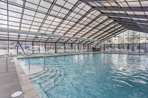 An indoor swimming pool with a glass ceiling, clear water, and white lounge chairs. - 2 Units at Holiday Hills Resort w/ Pools & Hot Tub (Branson)