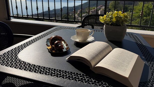 A table with a book, a cup, and a pastry on a balcony with a view of mountains. - Sunset luxury apartment (Tučepi)