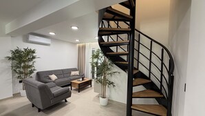 A modern living room with a grey sofa, a wooden coffee table, and a spiral staircase. - Sunset luxury apartment (Tučepi)