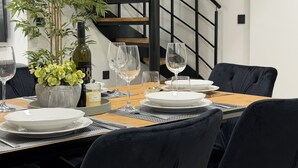 A dining table set with plates, glasses, and a bottle, surrounded by chairs and a potted plant. - Sunset luxury apartment (Tučepi)