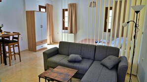 Un salon avec un canapé, une petite table, une armoire et un lit avec des rideaux.