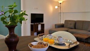 Une table à manger sur laquelle se trouve un plateau contenant un bol de viennoiseries, des verres de jus d’orange et une tasse de café.