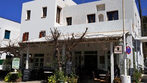 Un bâtiment blanc avec de nombreuses fenêtres, une enseigne et un panneau indiquant qu’il est interdit de se garer.