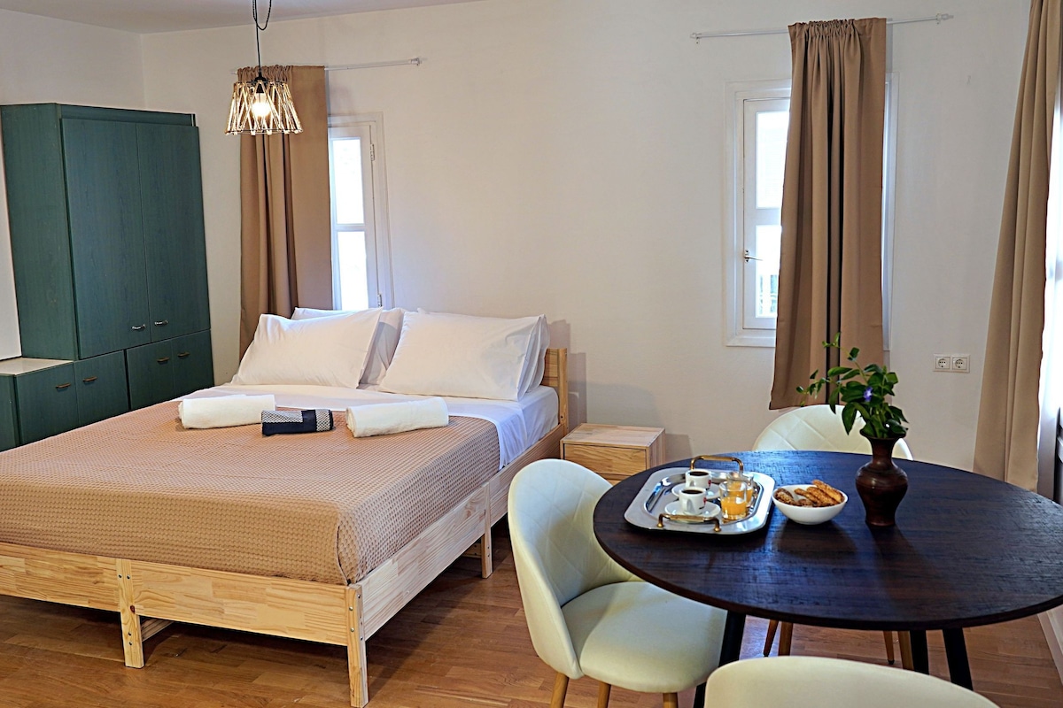 A bedroom with a bed, a wardrobe, a dining table with breakfast, and a window with curtains.