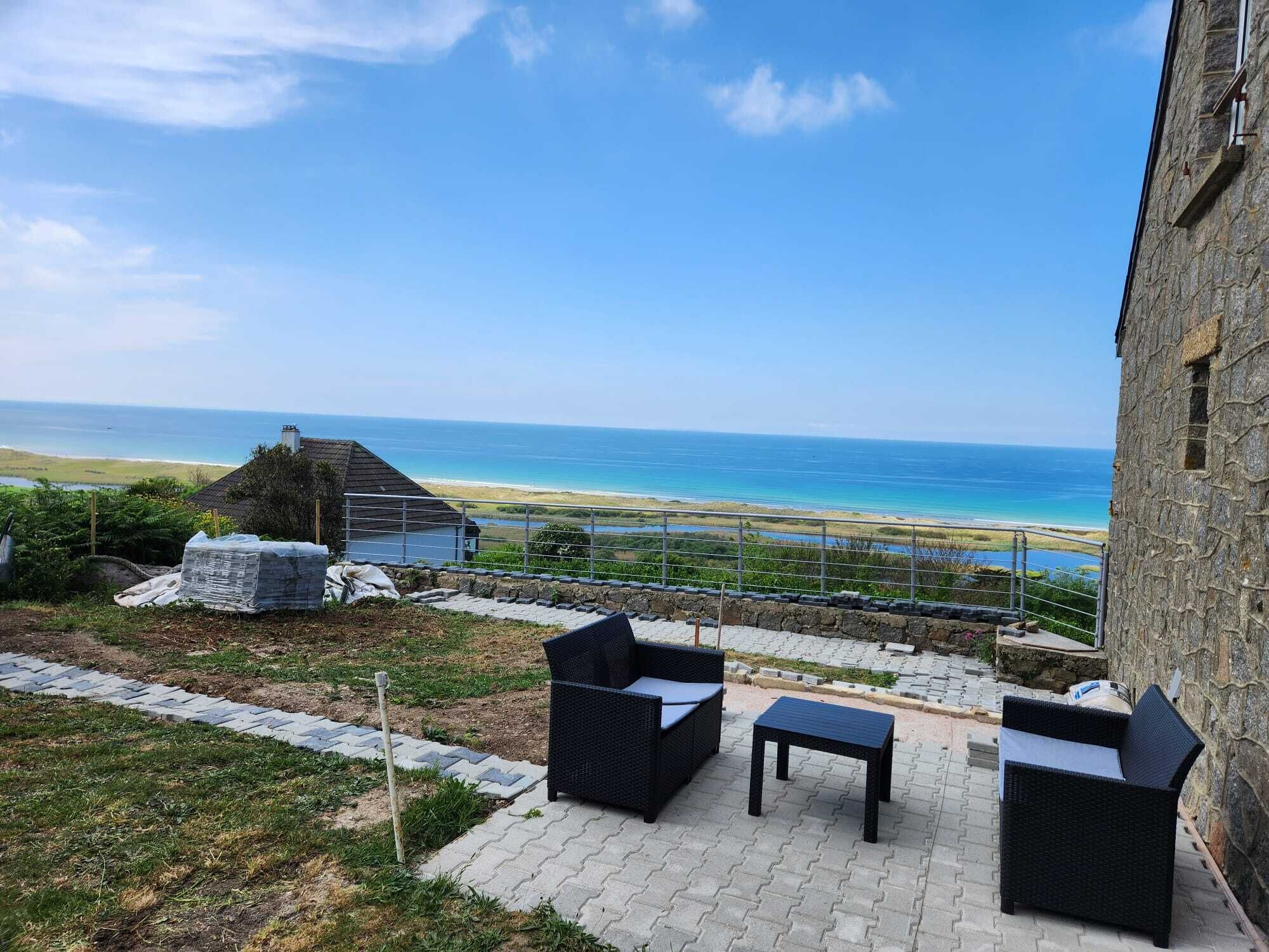 A patio with outdoor furniture overlooking a beach and ocean.