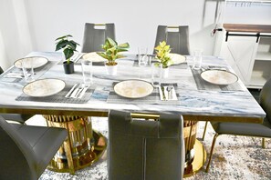 Uma mesa de jantar posta com pratos, copos, talheres e plantas em vasos.