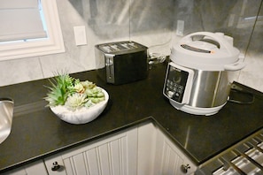 A kitchen with a toaster, a slow cooker, and a bowl of flowers on the counter.