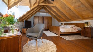 Une chambre avec un plafond en pente, des meubles en bois, une télévision, un lit et une chaise.