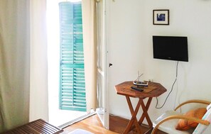 A room with a wooden table, a television mounted on the wall, a window with blue shutters, and a door. - Lovely home in Podaca with WiFi (Podaca)