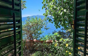 A view through open green shutters with a mountain and a body of water in the background. - Lovely home in Podaca with WiFi (Podaca)