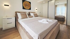 Ein modernes Schlafzimmer mit einem Bett, Nachttischen, einem Spiegel und einem Wandbild.