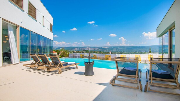 Une piscine sur le toit, avec des chaises longues, une table et une vue sur le paysage.