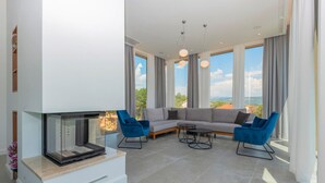 Un salon moderne doté d’une cheminée, d’un canapé d’angle et de grandes fenêtres offrant une vue panoramique.
