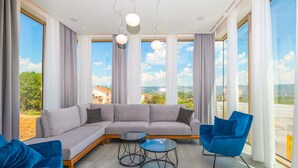 Un salon moderne avec un canapé d’angle, un fauteuil bleu et une table basse en verre.