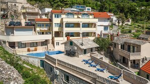 Et hotel med flere etager, en swimmingpool, udendørs siddepladser og udsigt over det omkringliggende bakkelandskab.