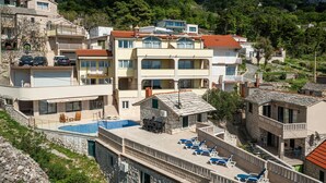 Un edificio de varios pisos con piscina, mobiliario exterior y fachada de piedra.