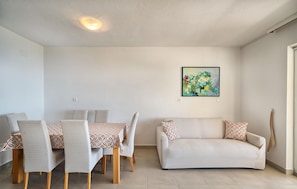 A living room with a sofa, chairs, a dining table, and a painting on the wall. - Amazing apartment in Bast with WiFi (Bast)