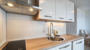 Una cocina moderna con estufa empotrada, lavaplatos de acero inoxidable y encimera de madera.