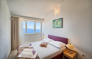 A hotel room with a bed, a nightstand, a lamp, a window with curtains, and a painting on the wall. - Amazing apartment in Bast with WiFi (Bast)