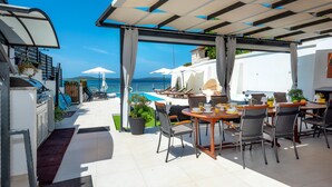 Una terraza con asientos al aire libre, piscina y vista al mar.