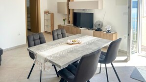 A dining area with a table, chairs, a TV, and a small kitchen area. - Beautiful apartment in Raslina with WiFi (Raslina)
