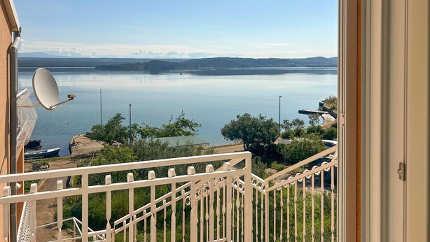 A balcony with a view of a calm lake, a satellite dish, and a distant mountain range. - Beautiful apartment in Raslina with WiFi (Raslina)