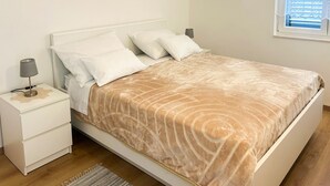 A neatly made bed with a patterned bedspread, a bedside lamp, and a nightstand with a lamp. - Beautiful apartment in Raslina with WiFi (Raslina)