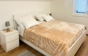 A neatly made bed with a patterned bedspread, a bedside lamp, and a nightstand with a lamp. - Beautiful apartment in Raslina with WiFi (Raslina)