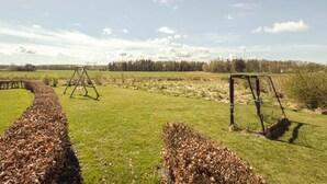 Un champ d’herbe avec deux balançoires et un tas de feuilles.
