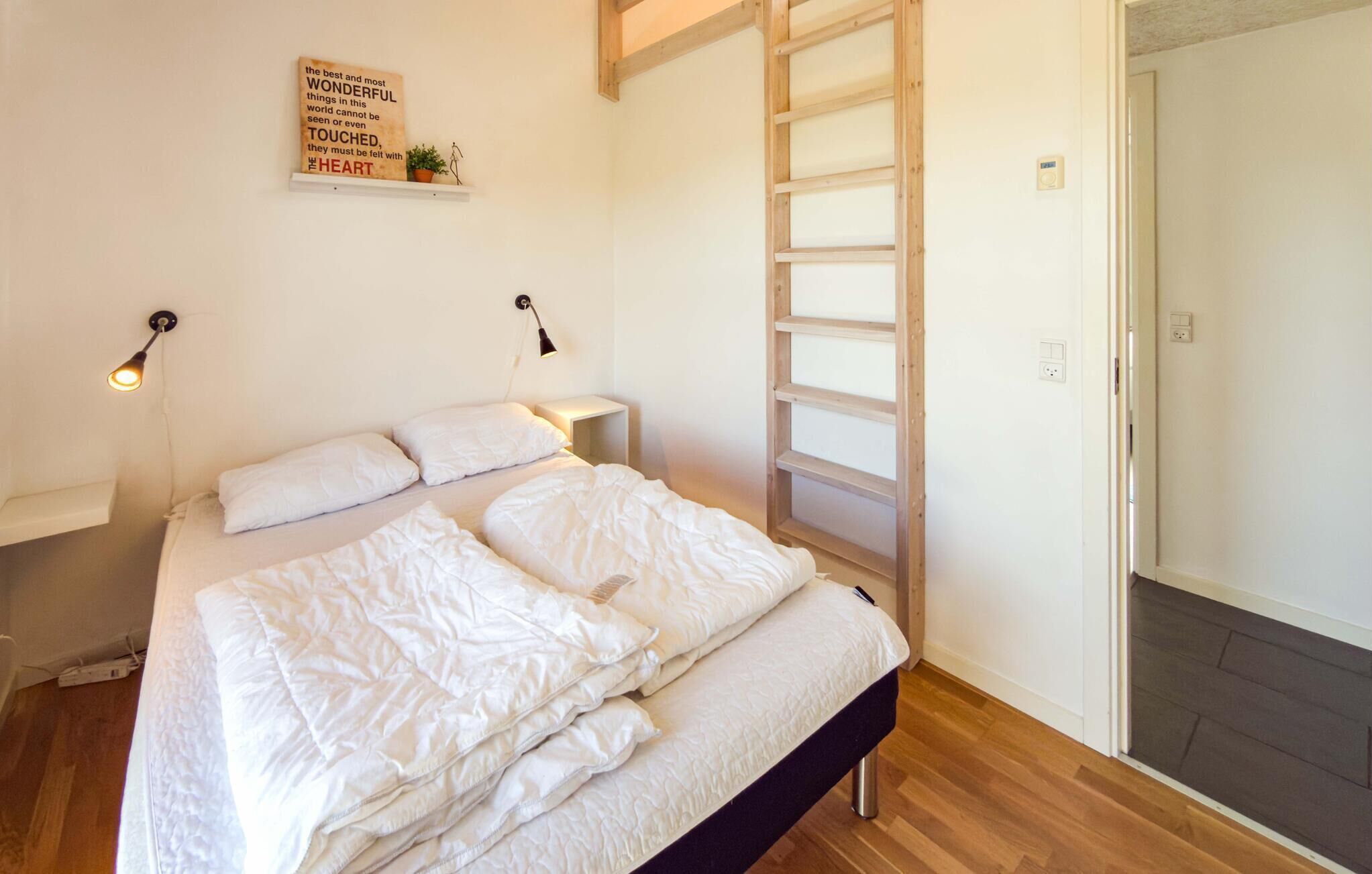 Ein Schlafzimmer mit Bett, einer Leiter, einer Wandleuchte und einem motivierenden Zitat.