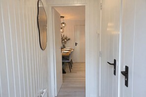 Un couloir comprenant un coin repas, un miroir et une porte dotée d’une poignée noire.