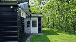 Un edificio moderno con facciata nera, una porta bianca e una piccola struttura adiacente con tetto a tegole.