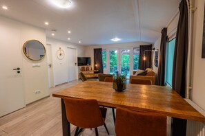 Ein moderner Essbereich mit Holztisch, orangefarbenen Stühlen und einem Blumentopf.