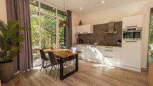 Una cucina moderna con zona pranzo, ampie finestre e una pianta in vaso.