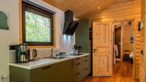 Una cocina compacta con ventana, cafetera y lavamanos.