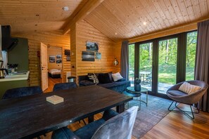 Ein gemütliches Blockhaus-Interieur mit Essbereich, Sofa und Blick ins Freie.