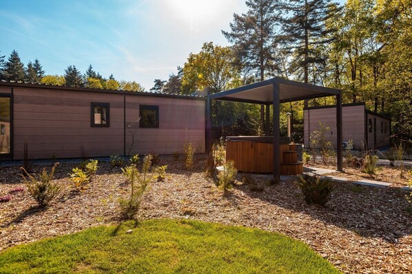 Ein modernes Blockhaus mit überdachter Außenbereich und Whirlpool.