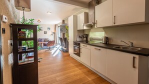 A modern kitchen with wooden flooring, white cabinets, and a built-in oven. - Vakantiepark De Wiltzangh - De Havezate Wellness (Ruinen)