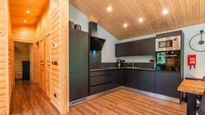 A modern kitchen with wooden walls, a built-in oven, and a microwave. - De Wiltzangh - Esborg Lodge Hottub | 6p (Ruinen)