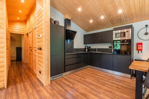A modern kitchen with wooden walls, a built-in oven, and a microwave. - De Wiltzangh - Esborg Lodge Hottub | 6p (Ruinen)